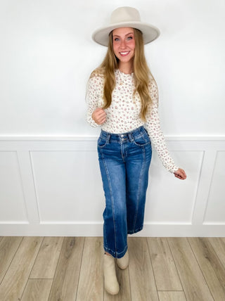 Patterned long-sleeve top, blue jeans, wide-brim hat, and beige boots