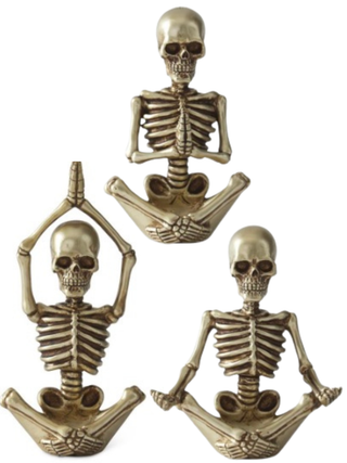 Three small decorative skeleton figurines in a metallic antique gold finish, each posed in a seated meditation yoga position against a plain white background.