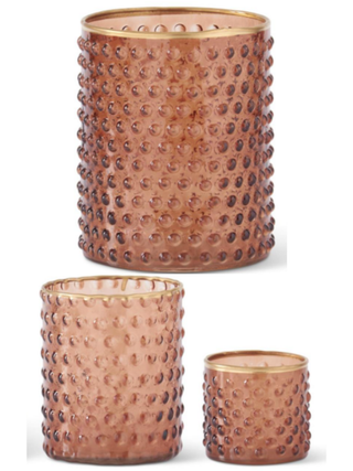 Three textured glass candle holders in a coppery rose gold color with gold rims, shown in different sizes against a white background.