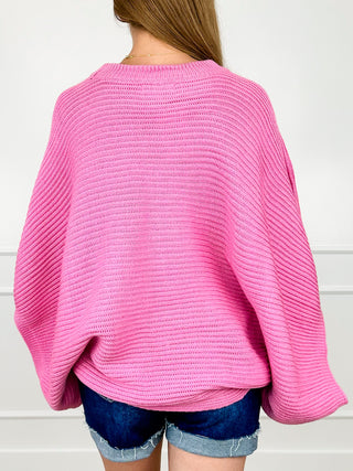Pink knit poncho top back view with ribbed texture and 3/4 sleeves