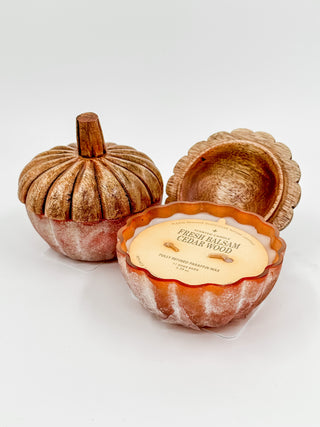 Orange-brown pumpkin wax candle with ridged wick and scalloped lid