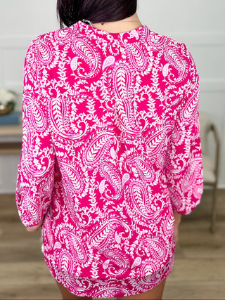Person wearing a pink and white patterned blouse in an indoor setting.