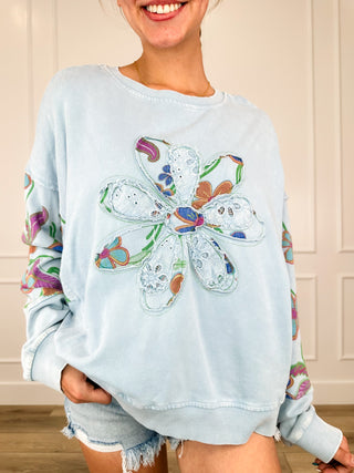 Light blue cotton long sleeve top with colorful front graphic and crew neckline