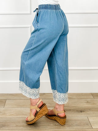 Medium-wash denim cropped wide-leg pants with elastic waist and lace-trimmed cuffs