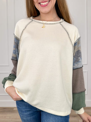 Cream knit long-sleeve top with camo raglan sleeves and rounded neckline