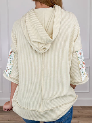 Cream ribbed hooded short sleeve top, back view with draped hood and floral sleeve panels