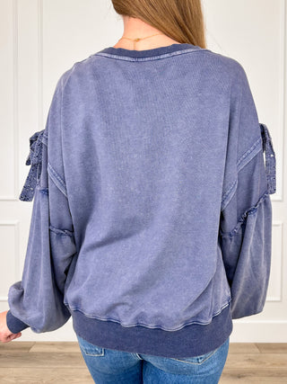Blue cotton-blend long sleeve top, back view, scalloped hem and tie-detailed cuffs