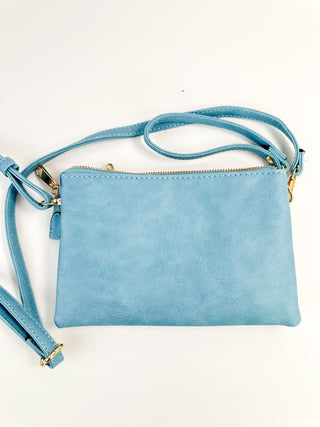 Blue faux leather crossbody handbag with top zip and adjustable shoulder strap