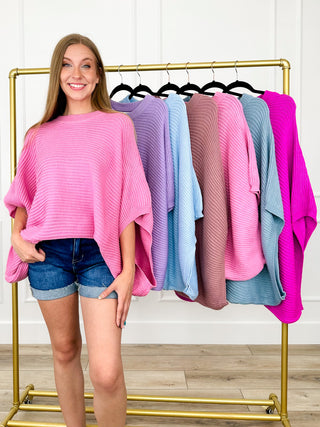 Pink knit poncho top with 3/4 sleeves and draped hem