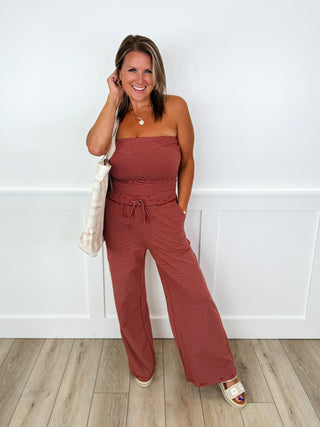 Maroon strapless jumpsuit with tied waist and wide-leg pants