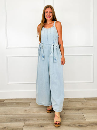 Light wash denim sleeveless jumpsuit with adjustable tie waist and wide legs