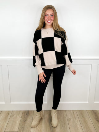 Checkered sweater and black leggings outfit with beige ankle boots
