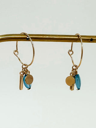 Gold hoop earrings with dangling blue and gold charms: round disk, small bar, and teal drop.