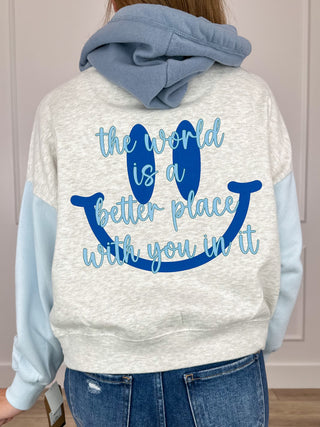 Back of cropped graphic hoodie with blue text slogan: “the world is a better place with you”