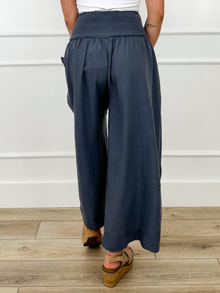 Dark blue high-rise wide-leg cropped pants with elastic waist, back view, pockets