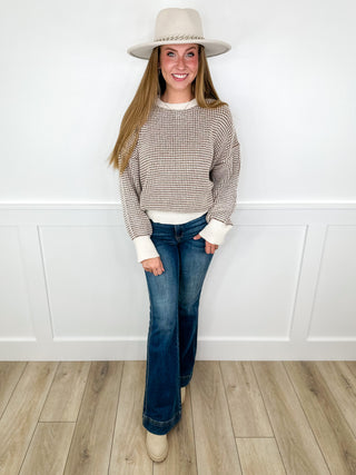 Beige knit sweater and blue jeans with light fedora hat