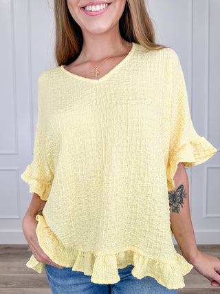 Lightweight short sleeve V-neck top in pale yellow with layered ruffle hem