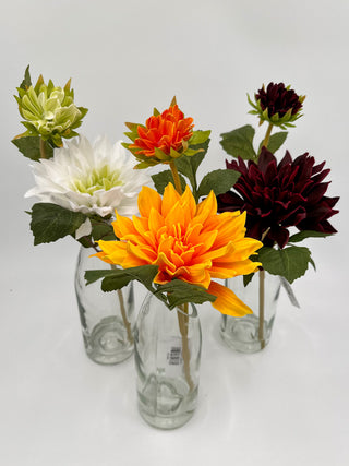 Assorted artificial dahlia flowers in clear glass vases: orange, white, dark red