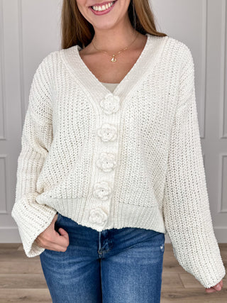 Ivory knit button-up cardigan with long sleeves and scalloped front buttons