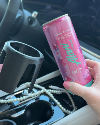 Pink energy drink can held in hand with printed label