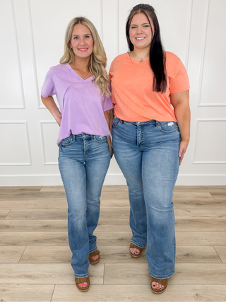 Two women’s outfits: lavender V-neck tee and blue denim jeans; coral V-neck tee and jeans