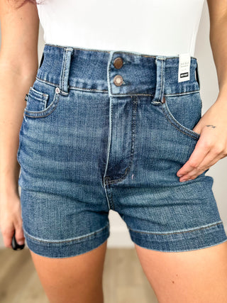 Blue denim shorts worn by a person on a neutral background