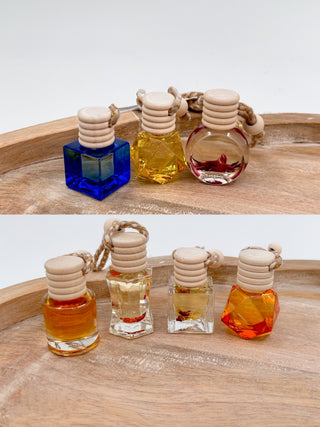 Assorted scent diffuser bottles with cork caps and braided cords in blue, yellow, clear, and red.