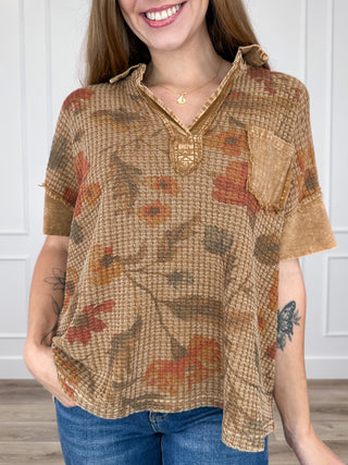 Brown short-sleeve knit top with floral print, collared V-neck and button placket