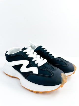 Black faux leather low-top sneakers with white laces and gum sole