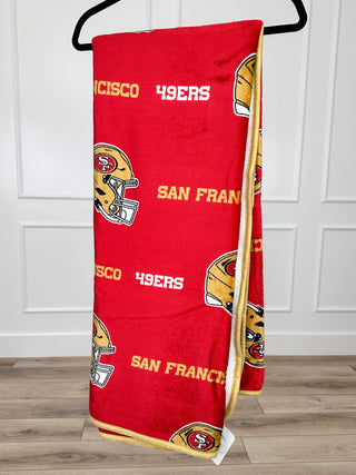 Red San Francisco 49ers sherpa blanket with repeated team text and helmet icons