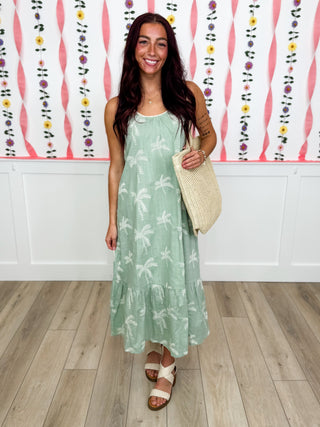 Mint green sleeveless floral maxi dress with tiered hem, paired with woven crossbody bag