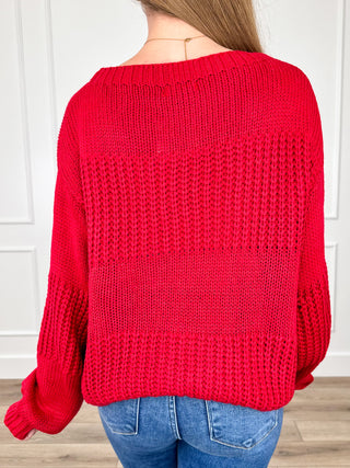 Red knit long-sleeve sweater back view with textured open-knit pattern.