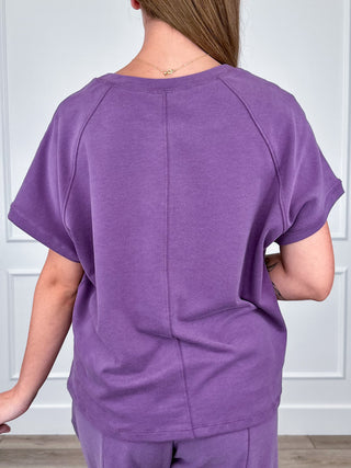 Purple short-sleeve crewneck top from back with seam detail and relaxed fit