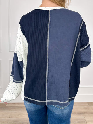 Back view: dark blue long-sleeve top with vertical seam and ivory contrast trim