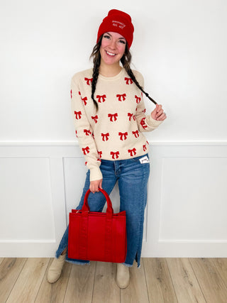 Women’s outfit set: cream sweater with red bow print, blue jeans, red beanie and tote bag