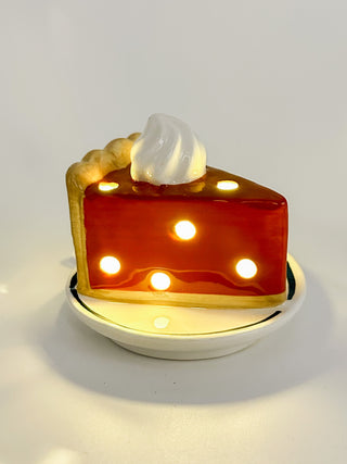 Ceramic light-up cake slice shelf sitter with orange-red frosting and glowing bulbs.