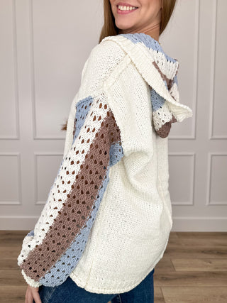 Cream knit hooded long-sleeve sweater with striped blue and brown crochet sleeve