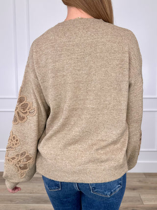 Tan knit long sleeve sweater top with floral embroidery on sleeve, back view