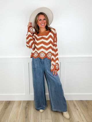 Chevron knit sweater and wide-leg jeans outfit, orange-white zigzag with floral cuffs.