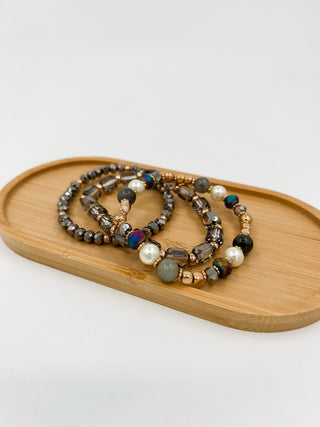 Beaded bracelet set with dark beads, blue accents, pearls, and gold-tone details