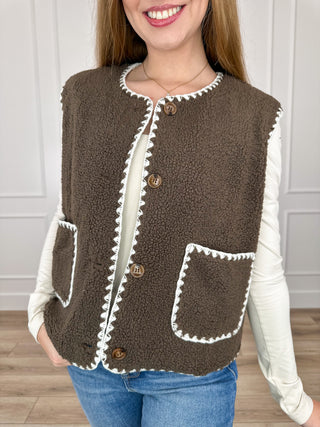 Brown sherpa vest with white trim, button front, and chest pocket