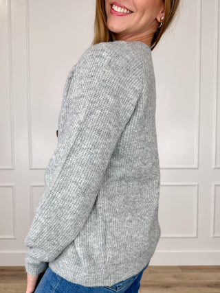 Grey knit cardigan with long sleeves; side view showing ribbed cuffs and hem