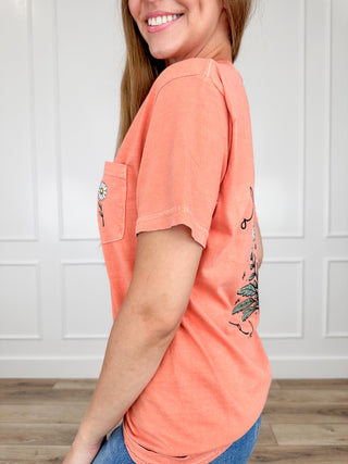 Orange short-sleeve graphic tee, side view, small daisy pocket