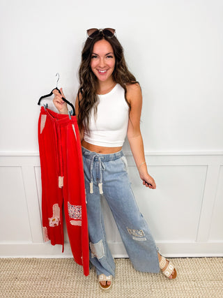 Womens outfit: white sleeveless crop top and light blue wide-leg jeans, with red dress on hanger.