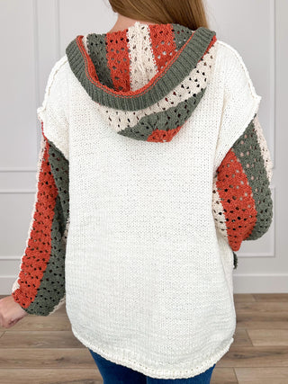 Cream hooded knit cardigan with patchwork hood and sleeves in red, gray, and dark green