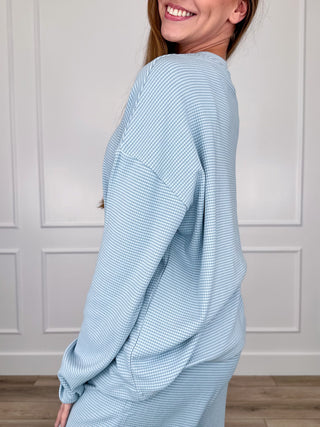 Light blue long-sleeve crewneck top, draped relaxed fit, textured weave