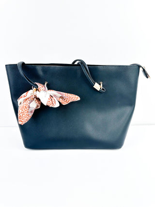 Dark blue faux leather tote bag with top handles and patterned ribbon bow charm