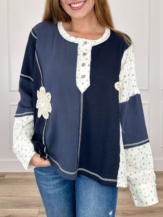 Dark blue long-sleeve top with ivory contrast button placket and trim