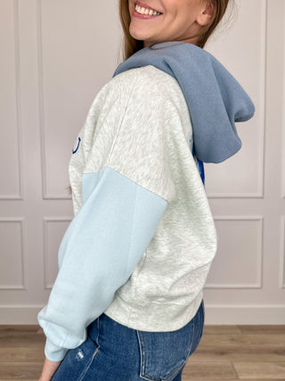 Cropped hoodie with heather grey body and light blue contrast raglan sleeves, side view