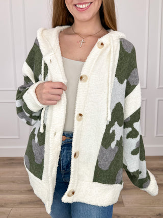 Hooded button-up camo cardigan with long sleeves, cream lining, wood-tone buttons